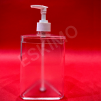Clear, triangular soap dispenser with a white pump on a red surface.