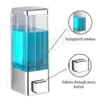 A close-up view of a chrome and transparent wall-mounted soap dispenser.
