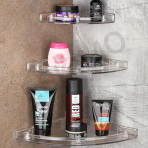 A set of three transparent Eskimo corner shelves mounted in a modern bathroom, organizing various grooming products.
