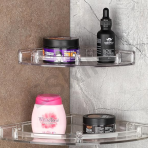 A close-up view of two wall-mounted clear Eskimo bathroom shelves holding toiletries on a modern tiled wall.